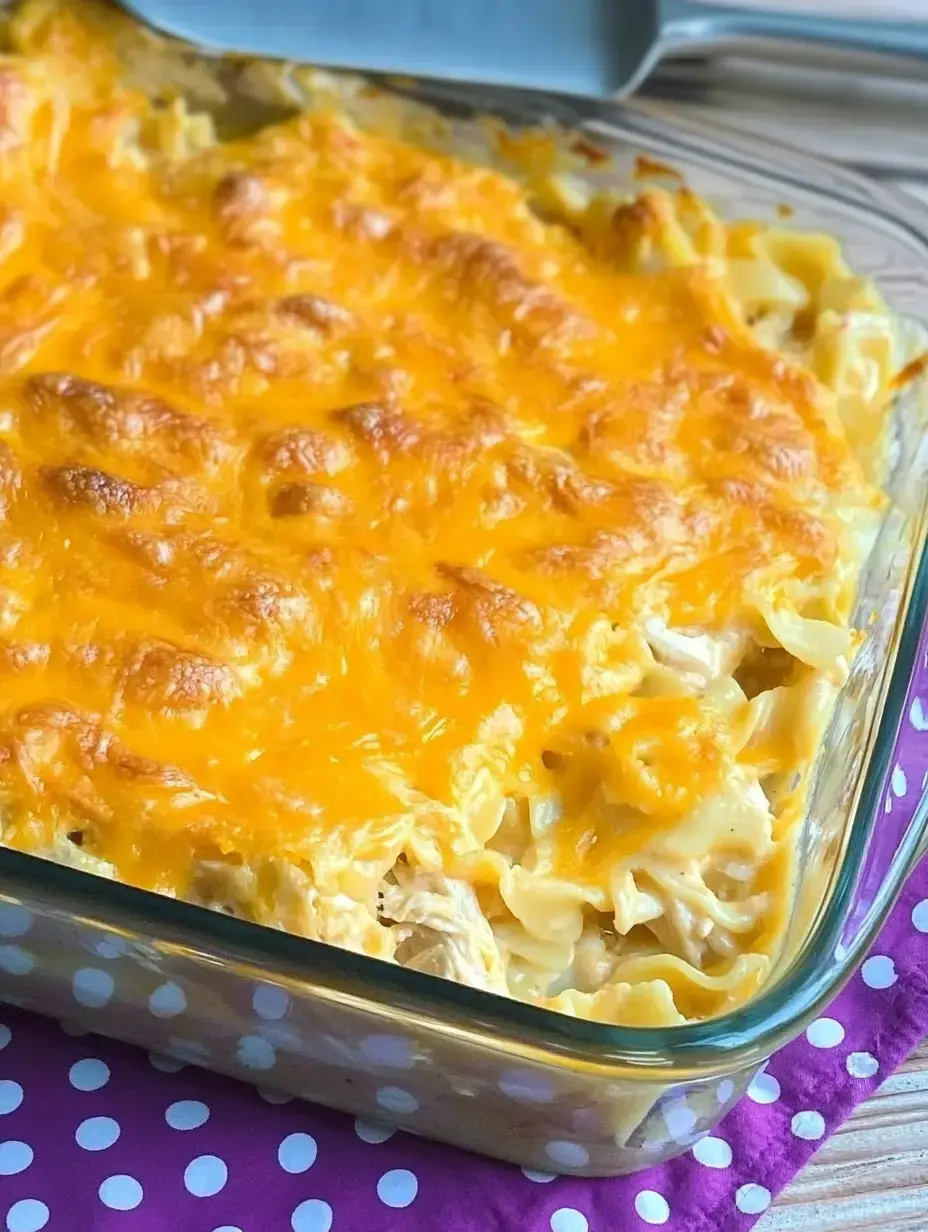Une vue rapprochée d'un gratin de pâtes cuit garni de fromage fondu dans un plat en verre sur un tissu à pois violets.