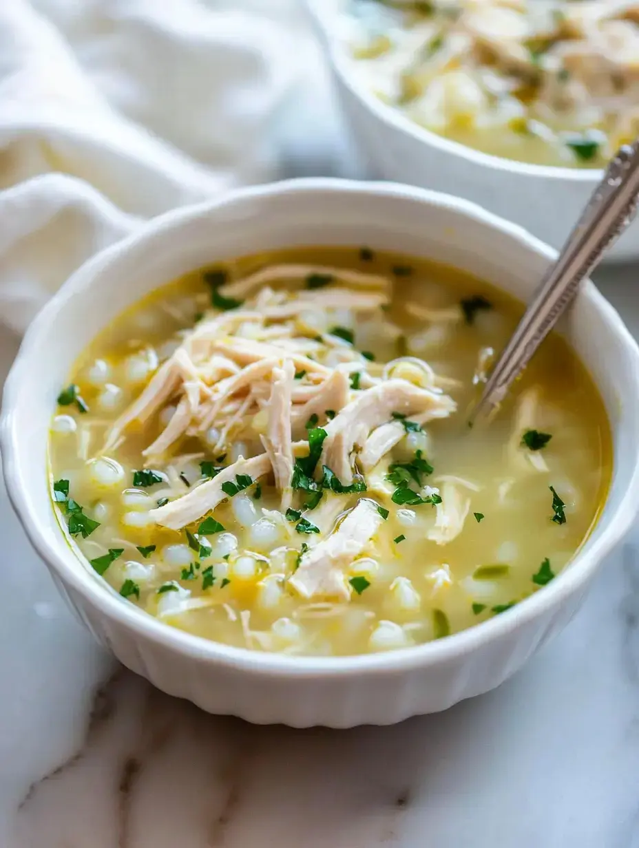 Un bol de soupe au poulet avec du poulet effiloché, du maïs et du persil saupoudré dessus.