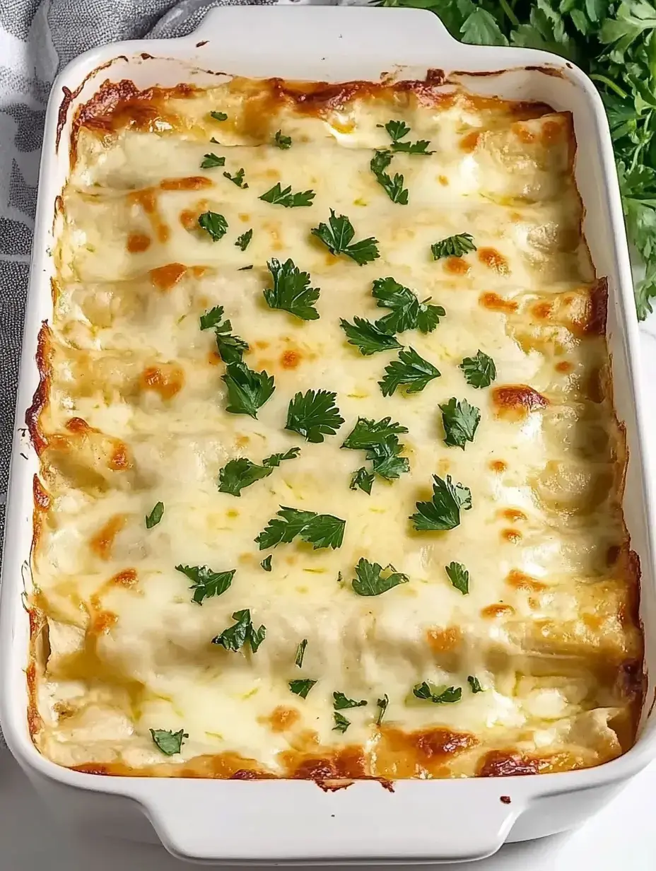 Un plat cuit d'enchiladas crémeuses recouvertes de fromage fondu et garnies de persil frais.