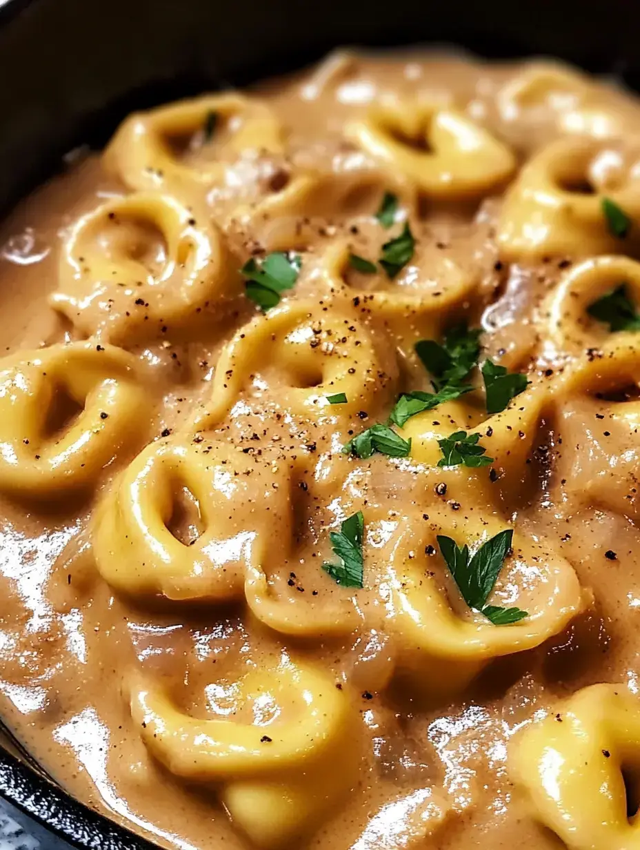 Une vue rapprochée de pâtes dans une sauce crémeuse, garnies de persil et de poivre noir.