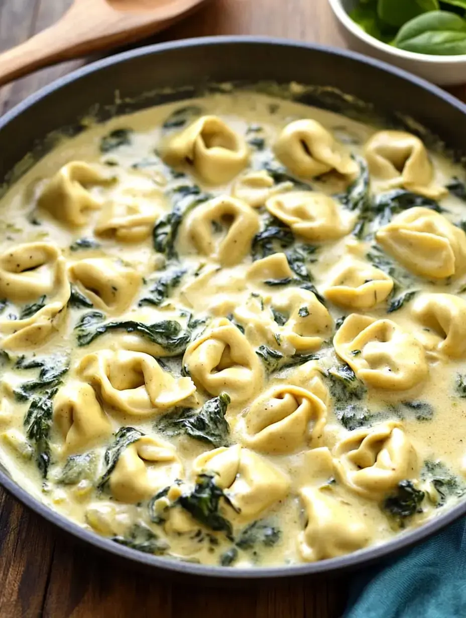 Une poêle remplie de tortellini dans une sauce crémeuse, garnie d'épinards.