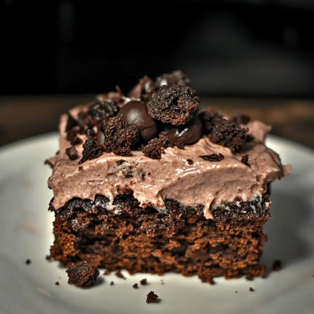 Une part de gâteau chocolat garnie de crème fouettée et biscuits chocolat émiettés.