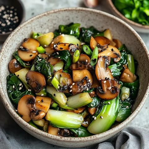 Un bol de champignons sautés et bok choy, décoré de ciboule et graines de sésame.