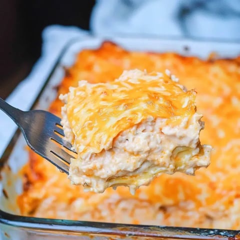 Une fourchette tient une part de lasagne crémeuse et gratinée, avec des couches de fromage et de pâtes fondantes.